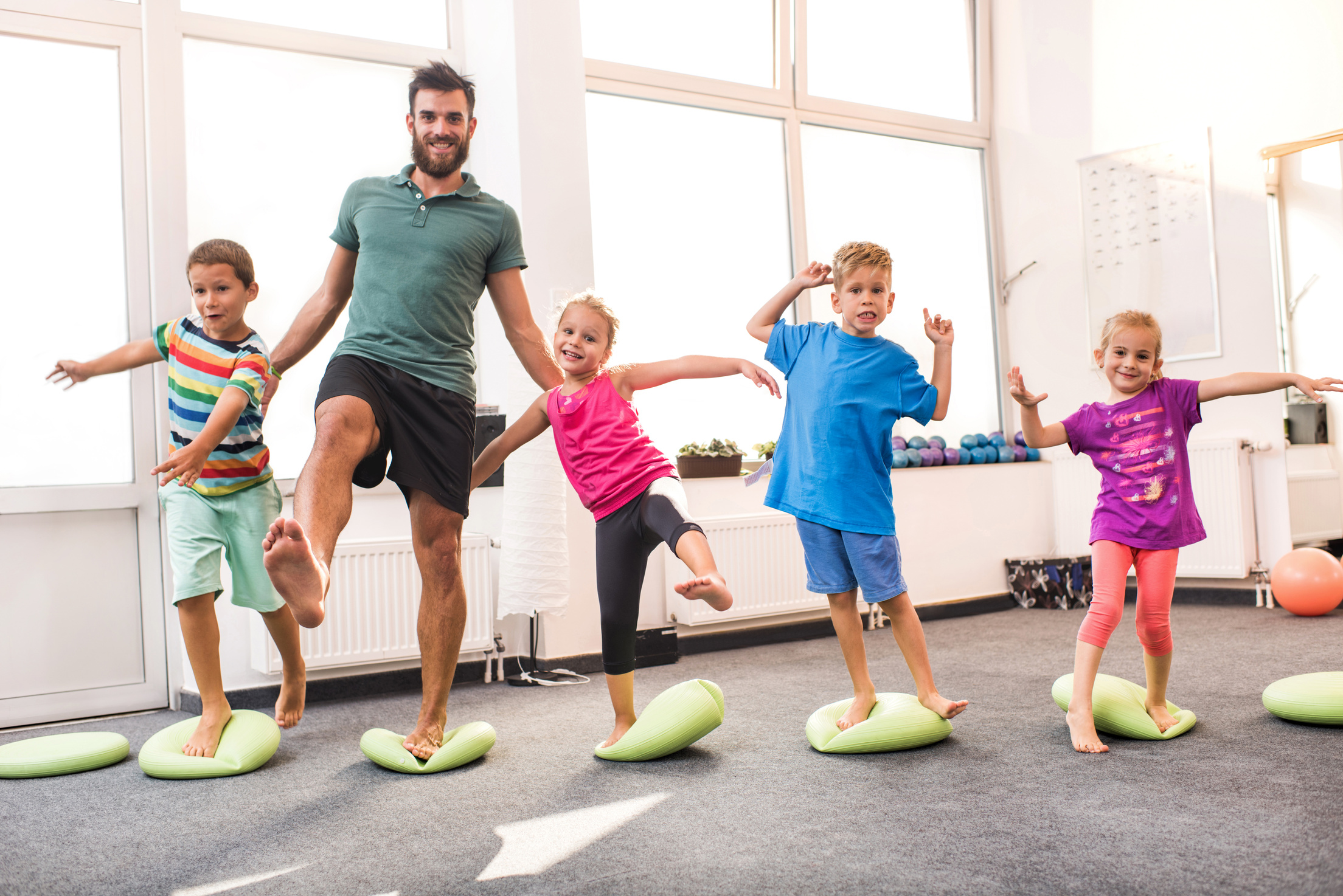 Happy children doing balance exercises with their coach.